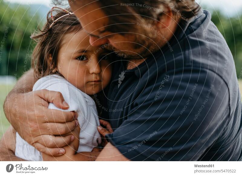 Vater umarmt Tochter, während er im Hinterhof sitzt Farbaufnahme Farbe Farbfoto Farbphoto Außenaufnahme außen draußen im Freien 2-3 Jahre 2 bis 3 Jahre