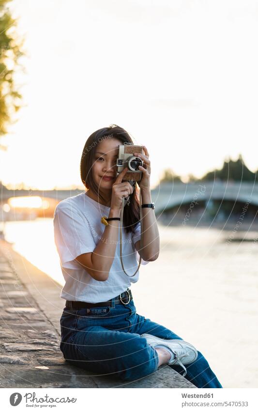Frankreich, Paris, Porträt einer jungen Frau mit Kamera am Fluss Seine bei Sonnenuntergang weiblich Frauen Fluesse Fluß Flüsse Kameras Portrait Porträts