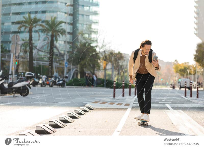 Mann schaut auf Handy beim Skateboardfahren in der Stadt Männer männlich Smartphone iPhone Smartphones skateboarden Skateboarden Skateboarding ansehen