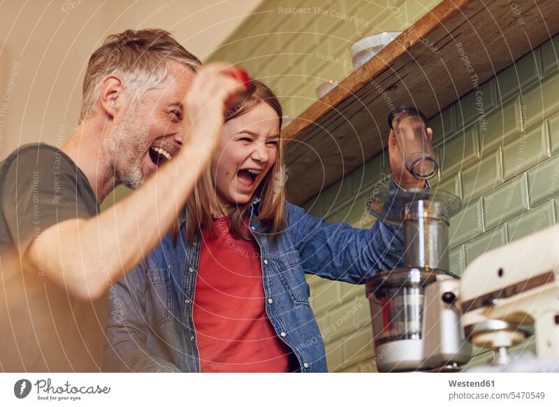Verspielte Vater und Tochter in der Küche beim Zubereiten eines Smoothie Geräte freuen Frohsinn Fröhlichkeit Heiterkeit Glück glücklich sein glücklichsein