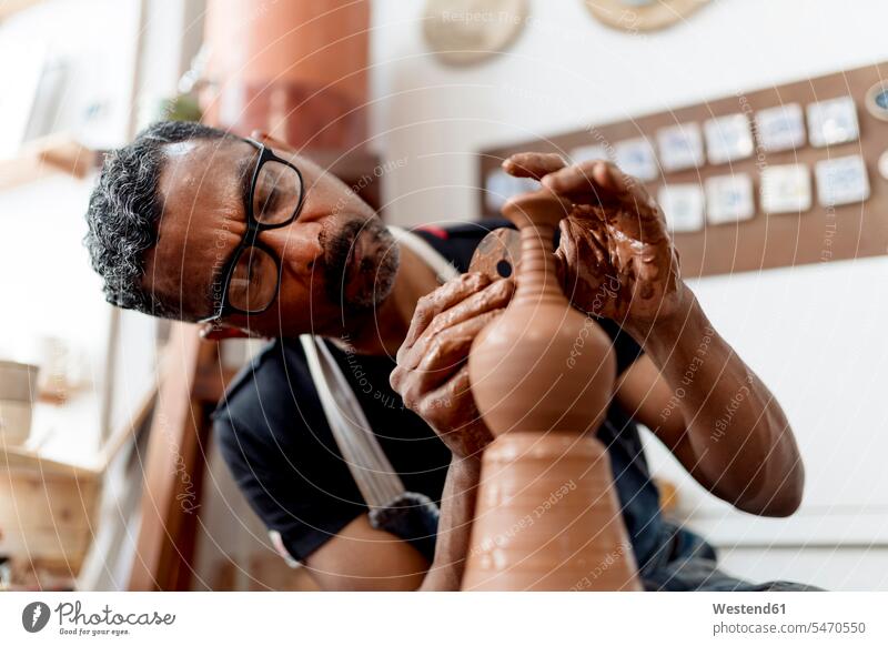 Nahaufnahme eines männlichen Künstlers, der Steingut herstellt, während er in einem Workshop sitzt Farbaufnahme Farbe Farbfoto Farbphoto Spanien Innenaufnahme