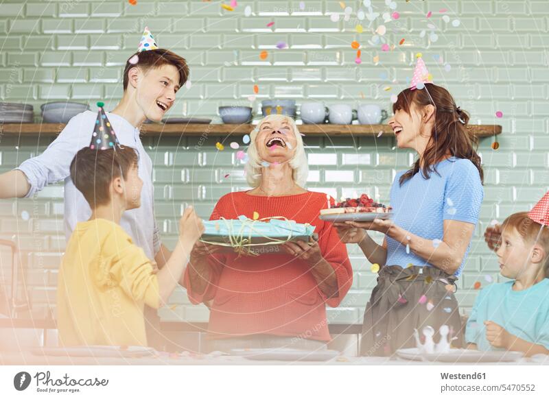 Mutter und Söhne feiern den Geburtstag der Großmutter in ihrer Küche Generation freuen Frohsinn Fröhlichkeit Heiterkeit daheim zu Hause witzig Miteinander