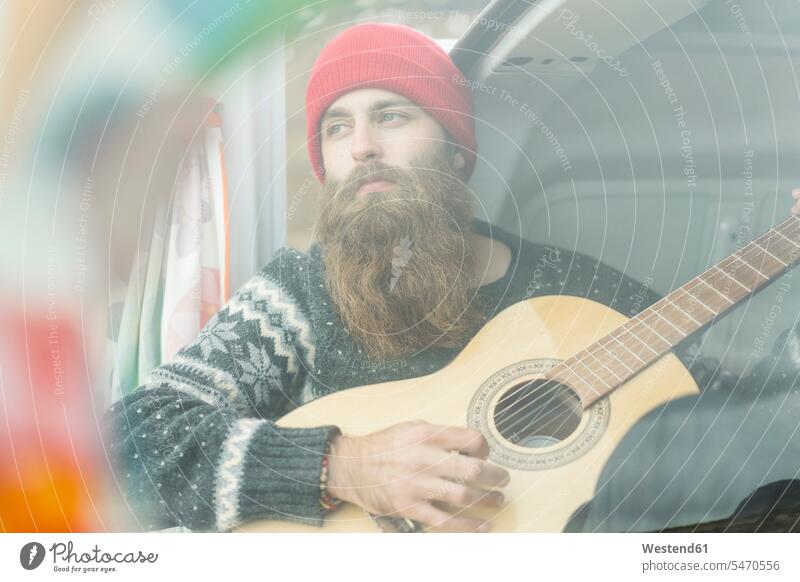 Porträt eines Hipsters im Lieferwagen beim Gitarrespielen Gitarren Mann Männer männlich Campingbus Kleinbus Kleinbusse Portrait Porträts Portraits