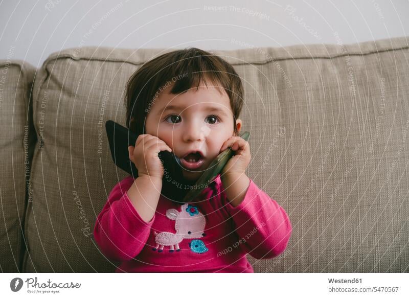 Kleines Mädchen spielt zu Hause mit zwei Mobiltelefonen telefonieren anrufen Anruf telephonieren Portrait Porträts Portraits spielen verspielt spielerisch