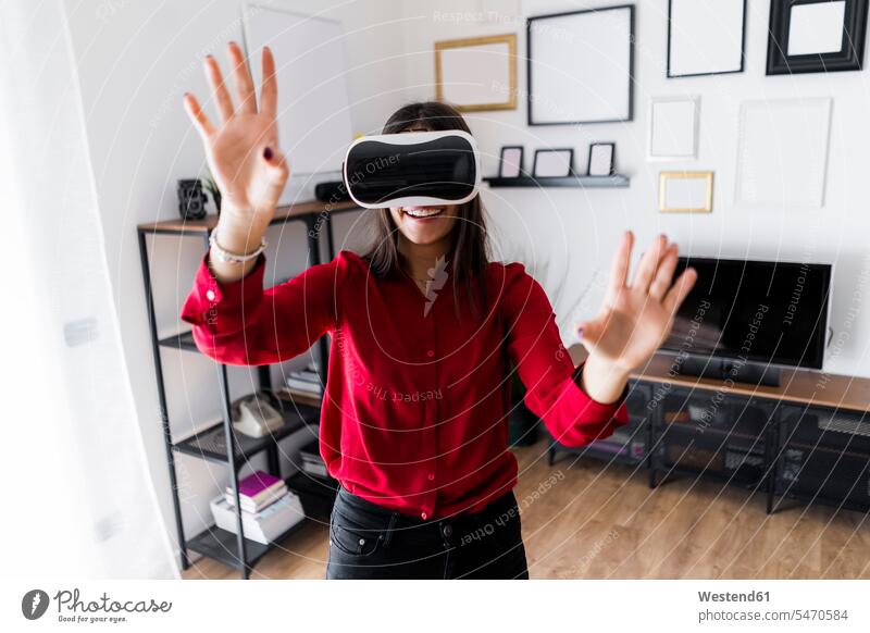 Junge Frau verwendet VR-Brille zu Hause geschäftlich Geschäftsleben Geschäftswelt Geschäftsperson Geschäftspersonen Businessfrau Businessfrauen Businesswoman
