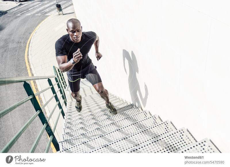 Mann in schwarzer Sportkleidung läuft Treppe hoch Treppenaufgang aufwärts nach oben hinauf Sportbekleidung Sportdress Kleidung Männer männlich schwarzen