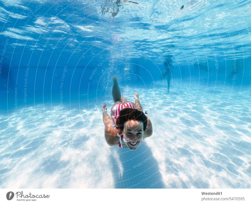 Glückliche Frau schwimmt unter Wasser im Pool eines Touristenortes Farbaufnahme Farbe Farbfoto Farbphoto Tag Tageslichtaufnahme Tageslichtaufnahmen