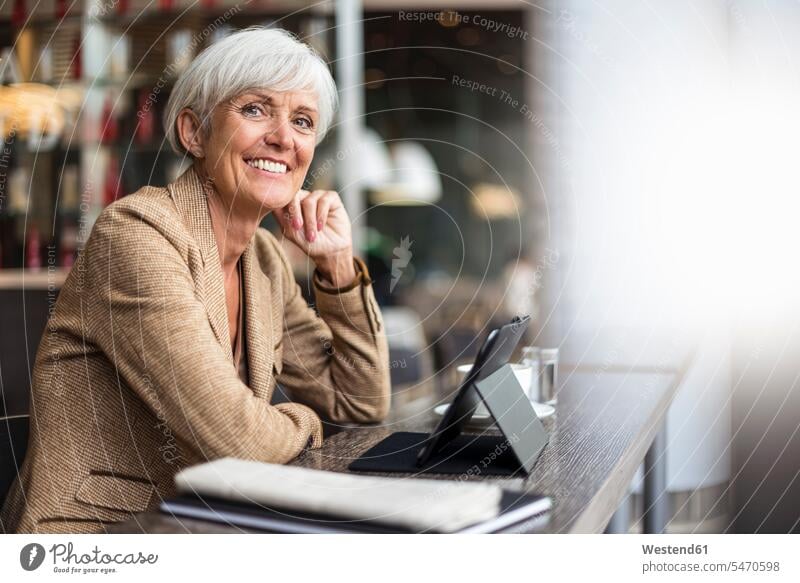 Porträt einer lächelnden älteren Geschäftsfrau mit Tablet in einem Café Geschäftsfrauen Businesswomen Businessfrauen Businesswoman Portrait Porträts Portraits