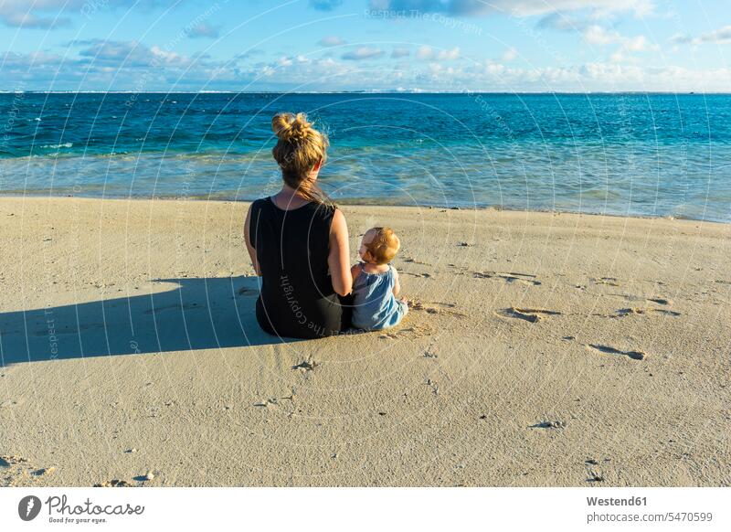 Cook-Inseln, Rarotonga, Frau sitzt mit ihrem Baby an einem weißen Sandstrand sitzen sitzend Tochter Töchter Gemeinsam Zusammen Miteinander Reise Travel Strand