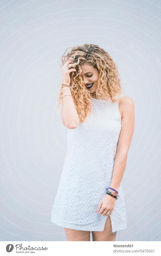 Porträt einer lächelnden jungen Frau mit blonden Locken in weißem Sommerkleid Farben Farbtoene Farbton Farbtöne weiss weißer weißes stehend steht Muße