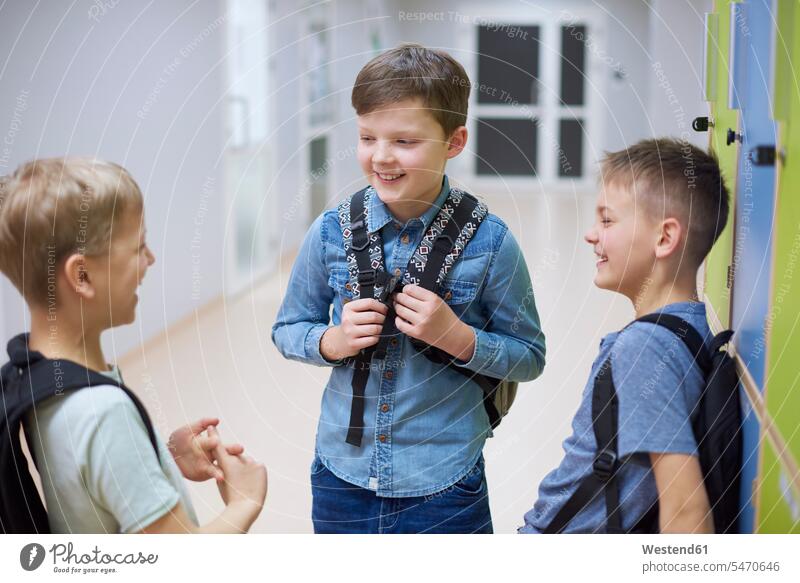 Fröhliche Schülerinnen und Schüler beim Spinden in der Schule sprechen reden Schrank Schließfach glücklich Glück glücklich sein glücklichsein Schulen Junge
