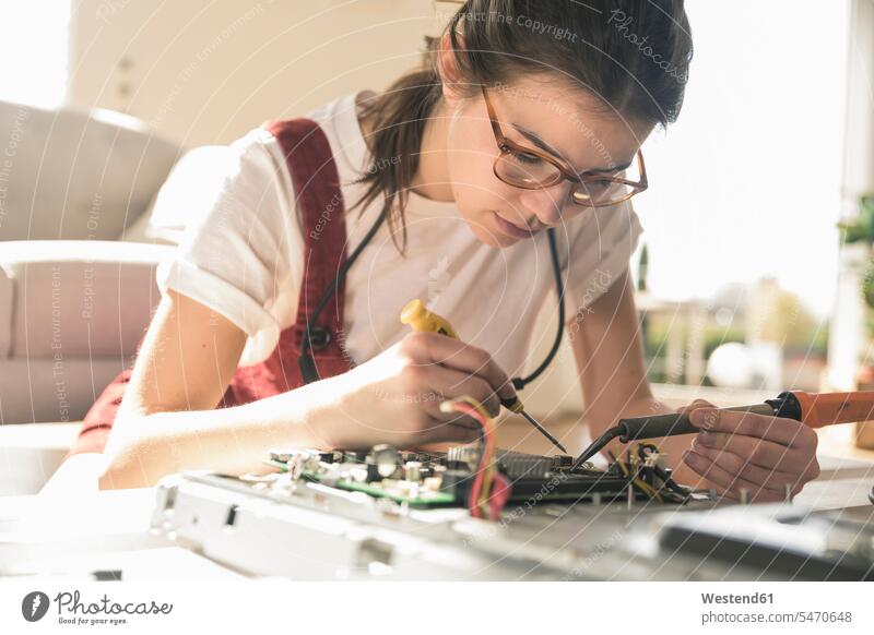 Junge Frau bei der Arbeit am Computer zu Hause Deutschland löten Schaltplatte Leiterplatine Printplatte Kompetenz Fähigkeit Können Wohnen Aufmerksamkeit