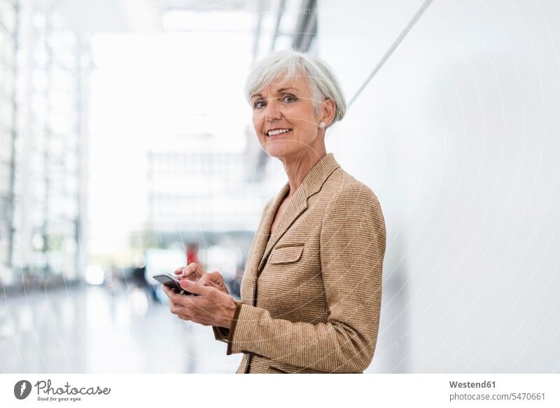 Porträt einer lächelnden älteren Geschäftsfrau, die ein Mobiltelefon benutzt Geschäftsfrauen Businesswomen Businessfrauen Businesswoman Frau weiblich Frauen