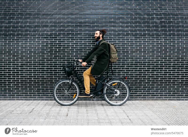 Mann fährt E-Bike entlang einer Ziegelmauer Fahrrad Bikes Fahrräder Räder Rad radfahren fahrradfahren radeln Backsteinwand Backsteinmauern eBikes E-Bikes