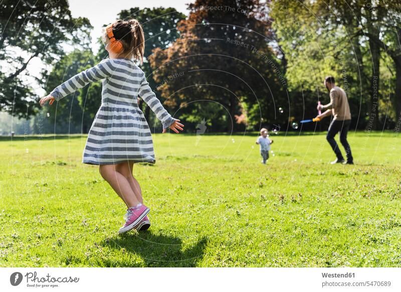 Mädchen mit Familie trägt Kopfhörer in einem Park aktiv weiblich Kopfhoerer Familien Parkanlagen Parks glücklich Glück glücklich sein glücklichsein Aktivität