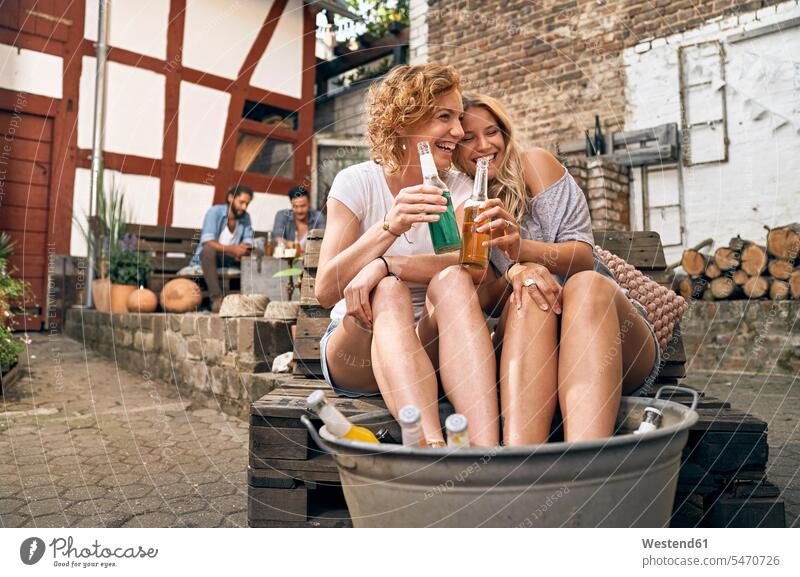 Freunde entspannen in einem Hinterhof im Sommer, junge Frauen kühlen ihre Füße in einer Wanne mit Getränken Sommerzeit sommerlich Party Parties Partys