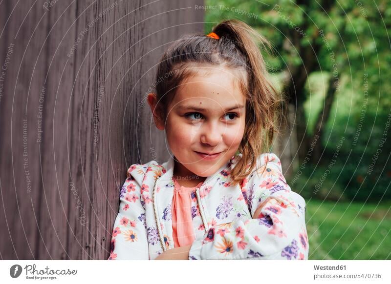 Porträt eines lächelnden Mädchens, das an eine Holzwand gelehnt ist Portrait Porträts Portraits Holzwände Holzwaende anlehnen angelehnt lehnend weiblich Wand