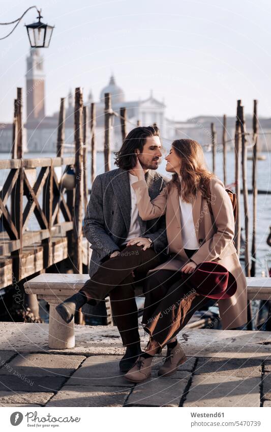 Junges Paar sitzt am Wasser in Venedig, Italien Hüte Jacken Bänke Sitzbank Sitzbänke Kuss Küsse sitzend entspannen relaxen entspanntheit relaxt freuen geniessen