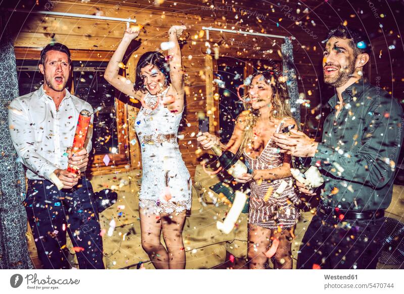Glückliche Freunde öffnen Champagner, während sie auf einer Party inmitten von Konfetti tanzen Farbaufnahme Farbe Farbfoto Farbphoto Innenaufnahme