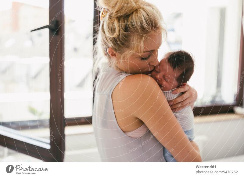 Mutter hält ihr weinendes Baby dicht an ihrer Schulter zu Hause halten Schultern Mami Mutti Mütter Mama Babies Babys Säuglinge Kind Kinder Zuhause daheim Mensch
