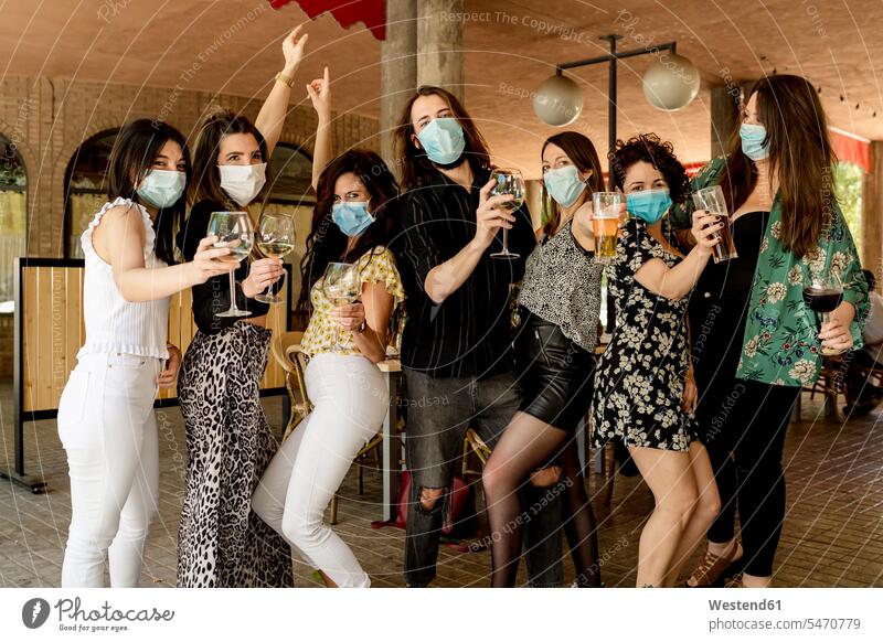 Junge männliche und weibliche Kunden, die während einer Pandemie Getränke halten, während sie im Restaurant stehen Farbaufnahme Farbe Farbfoto Farbphoto Spanien