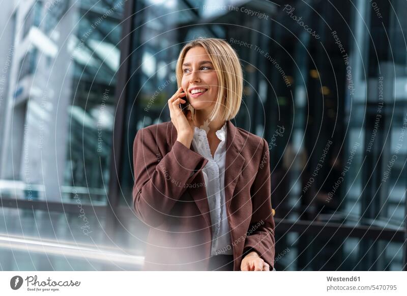 Lächelnde junge Geschäftsfrau am Telefon in der Stadt geschäftlich Geschäftsleben Geschäftswelt Geschäftsperson Geschäftspersonen Businessfrau Businessfrauen