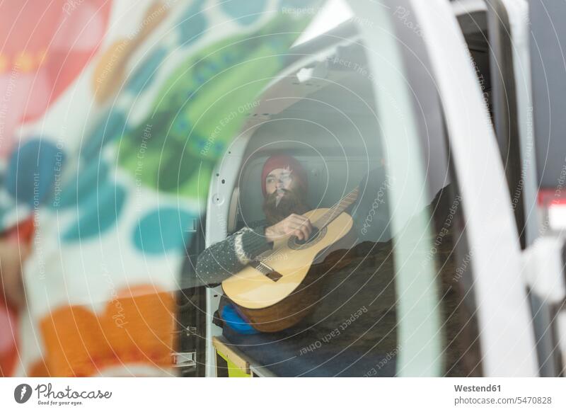 Mann liegt im Lieferwagen und spielt Gitarre liegen liegend Campingbus spielen Männer männlich Gitarren Kleinbus Kleinbusse Kraftfahrzeug Verkehrsmittel KFZ