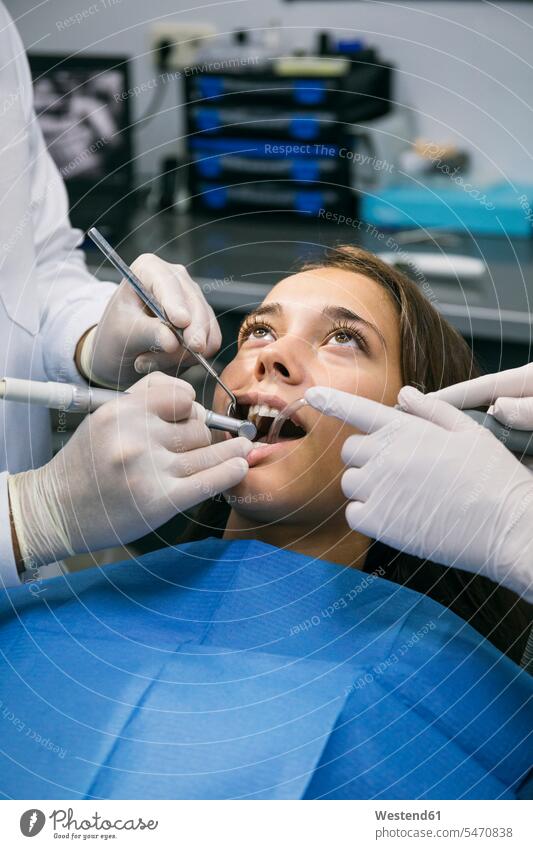 Zahnarzt mit chirurgischen Handschuhen, der die Zahnbehandlung einer Patientin mit Hilfe einer Assistentin in der Klinik durchführt Farbaufnahme Farbe Farbfoto
