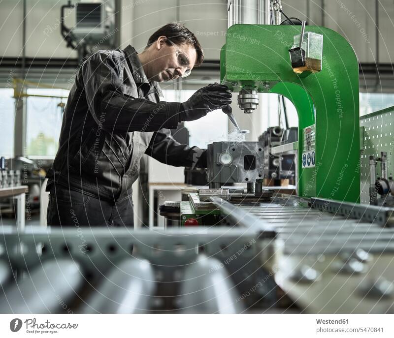 Arbeiter in metallverarbeitendem Betrieb belädt Zylinderkopf Maschine Maschinen Werkstatt Werkstätte Werkstaette Werkstaetten Werkstätten Fabrik Fabriken