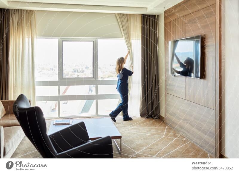 Zimmermädchen öffnet Vorhänge am Fenster im Hotelzimmer Farbaufnahme Farbe Farbfoto Farbphoto Innenaufnahme Innenaufnahmen innen drinnen Millennials