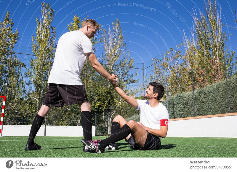 Fußballspieler hilft einem verletzten Spieler während eines Spiels Fußballplatz Fussballplatz Fußballplätze Fussballplaetze helfen mithelfen Hilfsbereitschaft