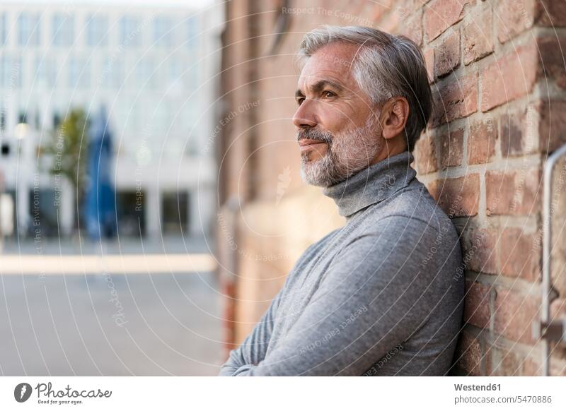 Porträt eines reifen Geschäftsmannes, der an einer Ziegelmauer lehnt Leute Menschen People Person Personen Europäisch Kaukasier kaukasisch 1 Ein ein Mensch