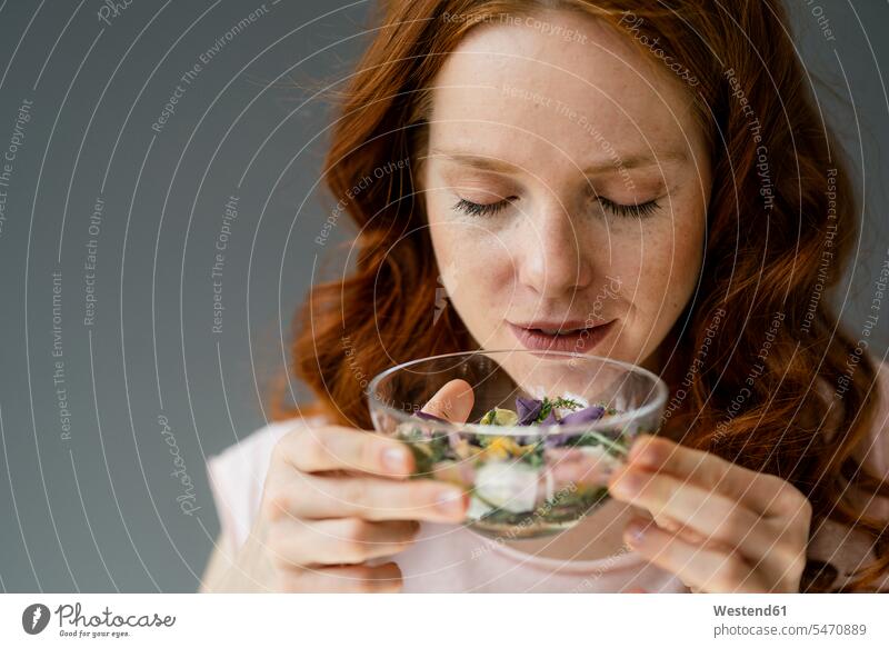 Porträt einer rothaarigen Frau, die an Blüten in einer Glasschale riecht entspannen relaxen entspanntheit relaxt freuen geniessen Genuss zufrieden Attraktivität