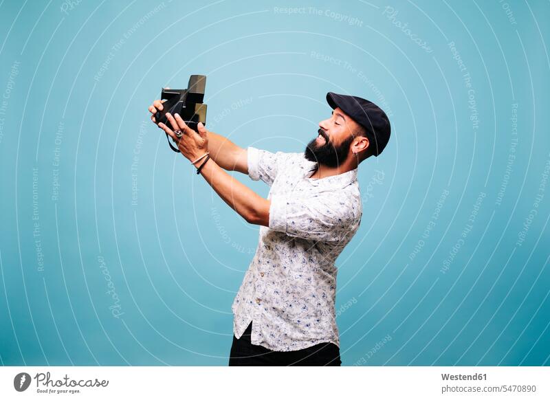 Bärtiger junger Mann im Studio macht Selfie mit Sofortbildkamera Fotografen Photograph Photographen Bilder Bildnis Fotos Polaroid Polaroids Sofortbilder Hemden