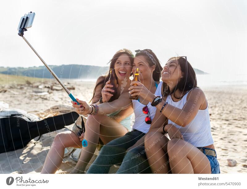 Glückliche Freundinnen mit Bierflaschen machen ein Selfie am Strand Leute Menschen People Person Personen Europäisch Kaukasier kaukasisch erwachsen Erwachsene