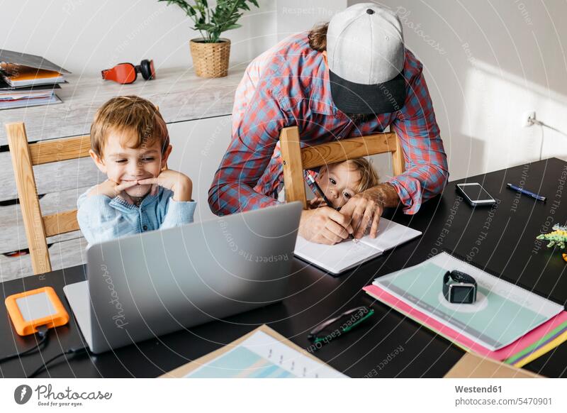 Vater schreibt in Notizbuch, während Kinder an seinem Schreibtisch spielen Tochter Töchter Arbeitstisch Schreibtische Sohn Söhne Notizbücher Notizbuecher
