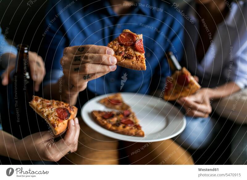 Nahaufnahme eines tätowierten Mannes mit Freunden, die eine Pizzascheibe halten Pizzastück Pizzastücke Pizzen Männer männlich Tattoo Tätowierungen Tatoos