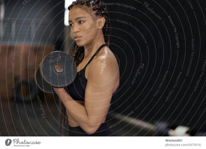 Selbstbewusste Sportlerin hebt Hanteln und schaut dabei weg, während sie im Fitnessstudio steht Farbaufnahme Farbe Farbfoto Farbphoto Südafrika Afrika