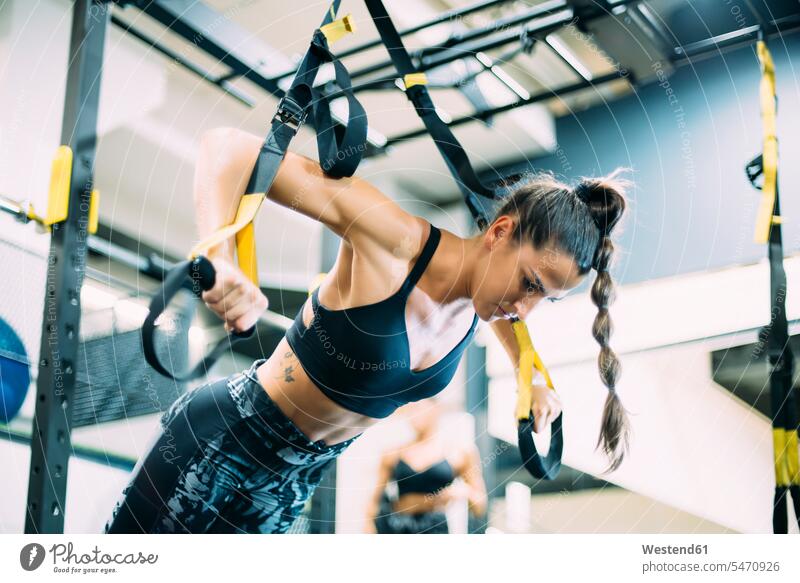 Junge Frau beim Suspensionstraining im Fitnessstudio ausüben trainieren Übung fit gesund Gesundheit Muße Leistungen Dynamik dynamisch Power konzentrieren