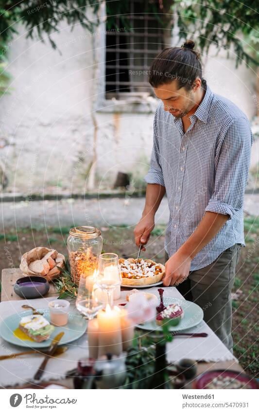 Mann arrangiert ein romantisches Essen bei Kerzenschein im Freien Männer männlich anrichten Kerzenlicht schwärmerisch schwaermerisch gefuehlvoll gefühlvoll
