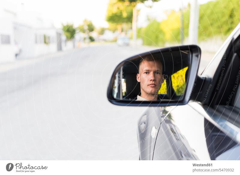 Spiegelung eines jungen Mannes im Außenspiegel eines Autos - ein