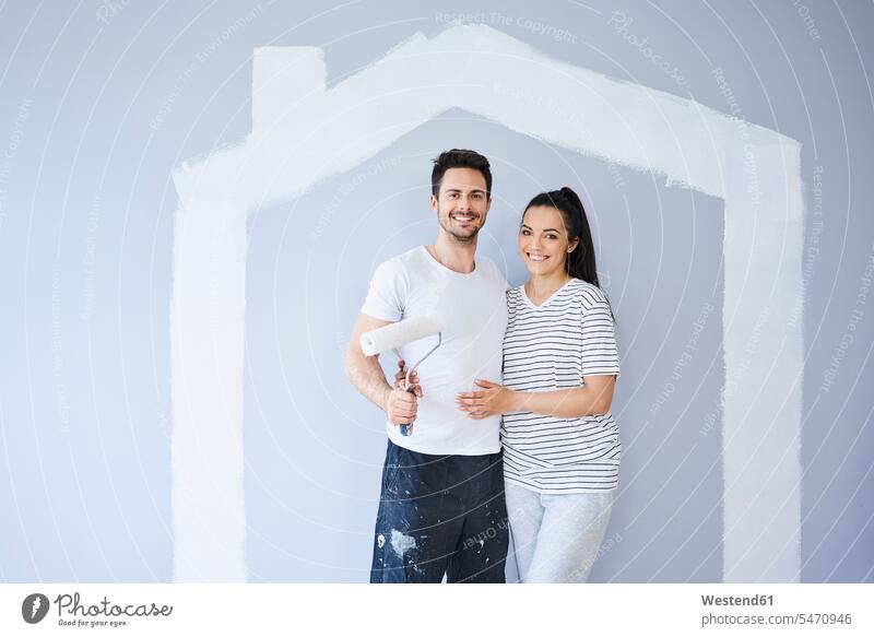 Porträt eines glücklichen Paares beim Malen in neuer Wohnung mit Hausform an der Wand Form Formen Portrait Porträts Portraits Glück glücklich sein glücklichsein