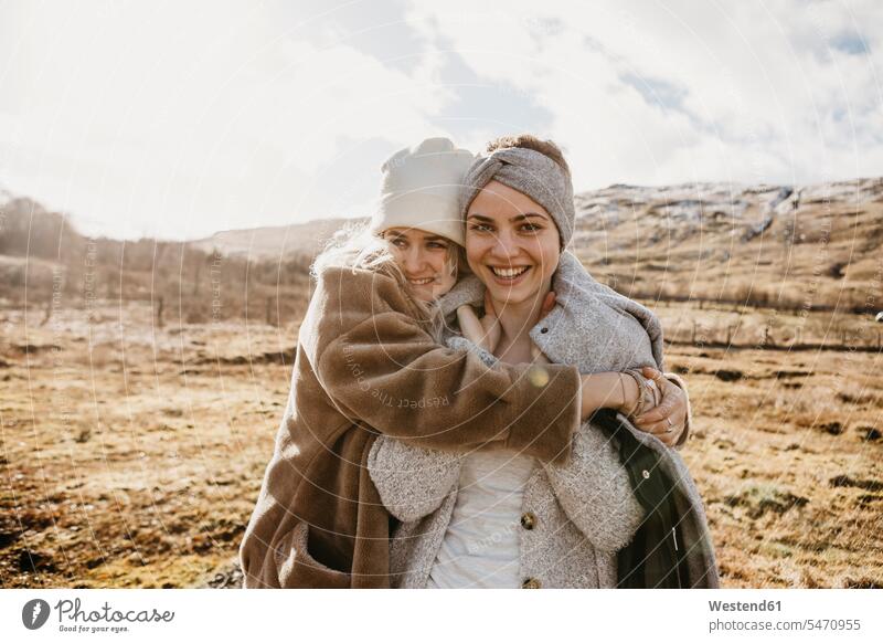 UK, Schottland, glückliche Freundinnen umarmen sich in ländlicher Landschaft Landschaften Portrait Porträts Portraits Glück glücklich sein glücklichsein Frau