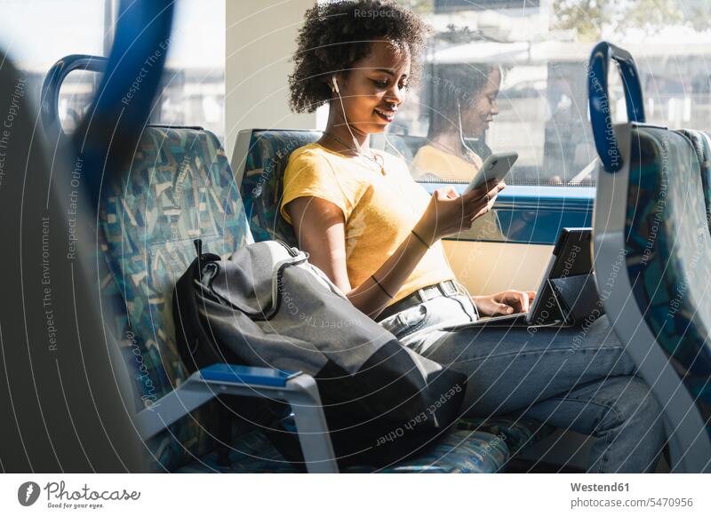 Junge Frau mit Kopfhörern mit Smartphone und Tablet im Zug Leute Menschen People Person Personen erwachsen jung Millennial 20 - 30 Jahre 20 bis 30