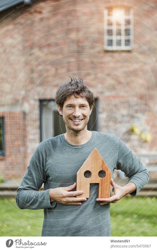 Porträt eines lächelnden Mannes vor dem Modell seines Wohnhauses Männer männlich Portrait Porträts Portraits halten Modelle Haus Häuser Haeuser Erwachsener