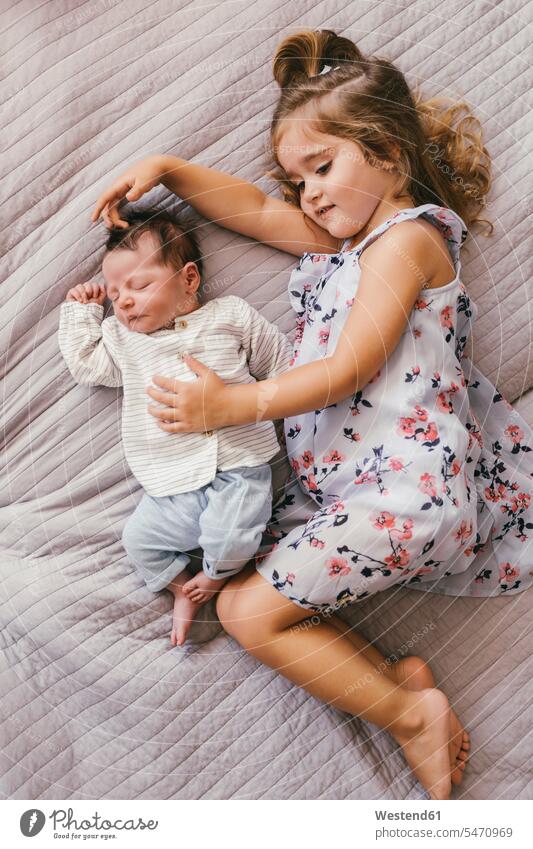 Mädchen liegend auf Decke kuscheln mit ihrem kleinen Bruder liegt lächeln Baby Babies Babys Säuglinge Kind Kinder schmusen knuddeln Decken weiblich Mensch