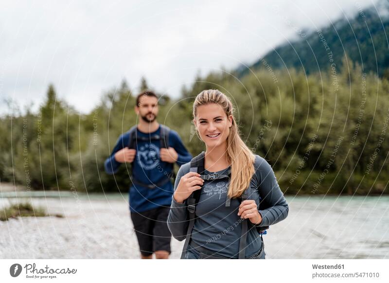 Junges Paar auf einer Wanderung am Flussufer, Vorderriss, Bayern, Deutschland Touristen Rucksäcke gehend geht freuen geniessen Genuss Glück glücklich sein
