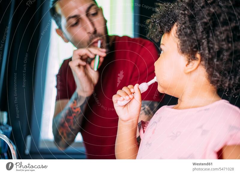 Nahaufnahme eines kleinen Mädchens mit Vater beim Zähneputzen im Badezimmer zu Hause Farbaufnahme Farbe Farbfoto Farbphoto Freizeitkleidung Freizeitbekleidung