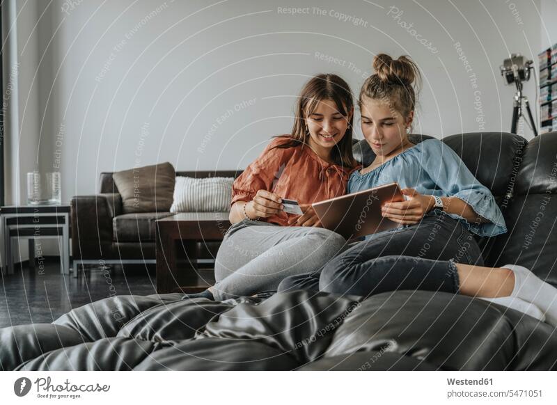 Freunde beim Online-Shopping über ein digitales Tablet, während sie sich zu Hause auf dem Sofa entspannen Farbaufnahme Farbe Farbfoto Farbphoto Deutschland
