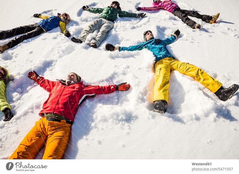 Gruppe von Freunden im Schnee liegend Touristen Jahreszeiten winterlich Winterzeit entspannen relaxen freuen geniessen Genuss Glück glücklich sein glücklichsein